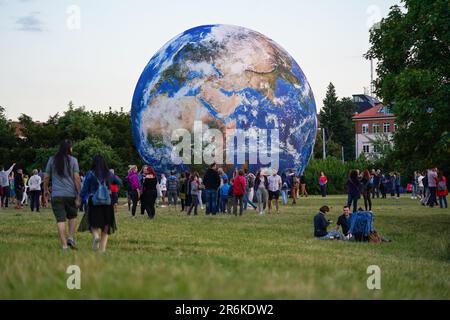 Brünn, Tschechien - 12. Juli 2020: Menschen, die vor dem aufblasbaren Erdmodell laufen, das auf einer grünen Wiese in der Nähe des Planetariumparks aufgestellt wurde Stockfoto