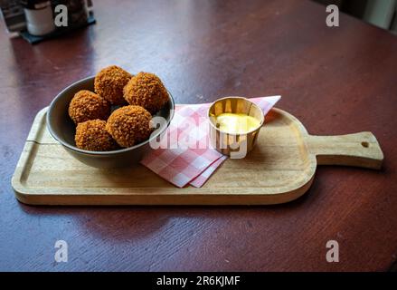 Bitterballen, ein typisch holländischer Snack ähnlich Kroketten, serviert mit Senfsauce, selektiver Fokus Stockfoto