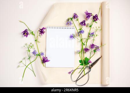 Aquilegia-Blumen, Notizbuch, leere Modelle, Draufsicht, Kopierraum. Sommermockup-Szene. Stockfoto