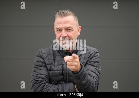 Ein Mann mittleren Alters, der in die Kamera zeigt Stockfoto