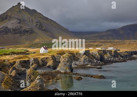 Ein klassischer Blick auf die Basaltlava-Klippen an der Küste im Dorf Arnastapi, umgeben von den Bergen von Snaefellsjokull Stockfoto