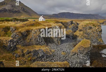 Ein klassischer Blick auf die Basaltlava-Klippen an der Küste im Dorf Arnastapi, umgeben von den Bergen von Snaefellsjokull Stockfoto