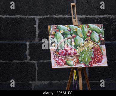 Farbenfrohes Aquarelle, noch lebendiges Gemälde der Künstlerin Rita Bobolari auf einer hölzernen Staffelei vor einer Steinmauer in Catania Stockfoto