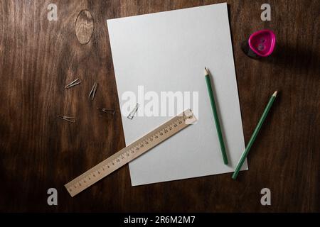 Stilleben mit Bleistiften, Schaberpapier und Bleistiftspitzer auf einem dunkelbraunen Tisch mit Holzstruktur Stockfoto