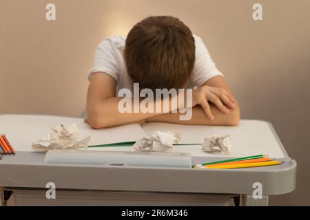 Ein 10-jähriger Schuljunge machte seine Hausaufgaben, sehr müde und schlief an seinem Schreibtisch Stockfoto