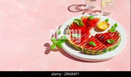 Gegrillte Wassermelonenscheiben mit Zitrone und Basilikum. Sommerdessert Stockfoto
