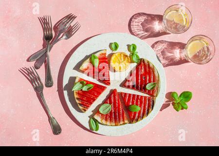 Gegrillte Wassermelonenscheiben mit Zitrone und Basilikum. Sommerdessert Stockfoto