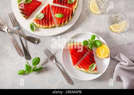 Gegrillte Wassermelonenscheiben mit Zitrone und Basilikum. Sommerdessert Stockfoto