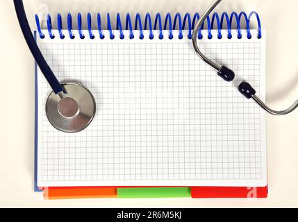 Offenes Buch und Stethoskop auf dem Schreibtisch Stockfoto