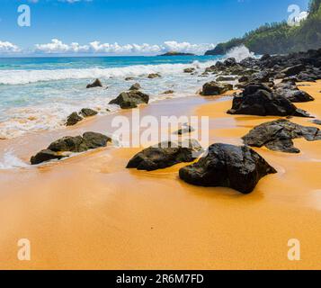 Exponiertes Lava Reef am Sandy Shore mit Kilauea Lighthouse in the Distance, Kauapea Beach, Kauai, Hawaii, USA Stockfoto