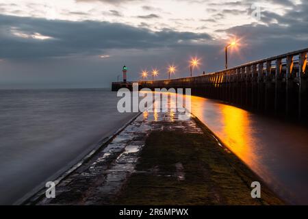 Ein Leuchtturm, der bei Sonnenuntergang am Pier in Nieuwpoort, Belgien, hoch am Dock steht Stockfoto
