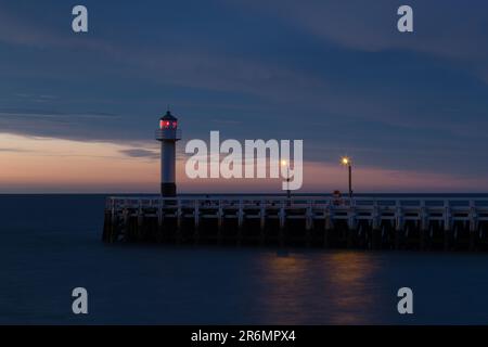 Ein Leuchtturm, der bei Sonnenuntergang am Pier in Nieuwpoort, Belgien, hoch am Dock steht Stockfoto