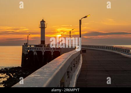Ein Leuchtturm, der bei Sonnenuntergang am Pier in Nieuwpoort, Belgien, hoch am Dock steht Stockfoto