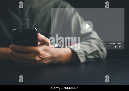 Mann, der Video-Streaming auf einem virtuellen Bildschirm mit einem Smartphone genießt Stockfoto