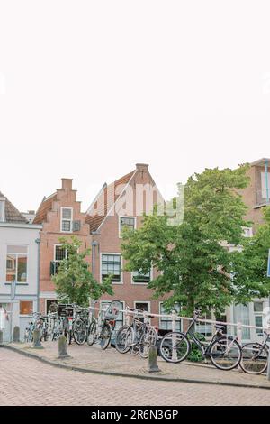 Ein typisches Bild aus einer kleinen niederländischen Stadt: Mehrere Fahrräder lehnen sich gegen eine Brücke über einen kleinen Fluss. Stockfoto