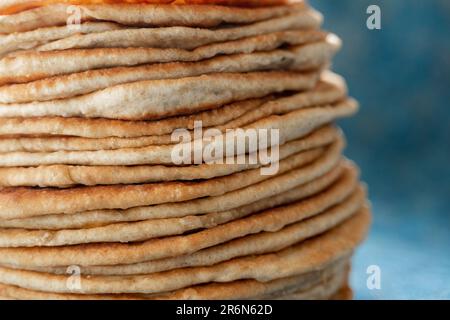 Fladenbrot Lavash, Chapati, Naan, ein Haufen Tortilla auf blauem Hintergrund hausgemachtes Fladenbrot gestapelt. Stockfoto