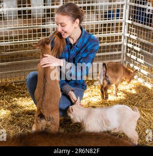 Bäuerin füttert und spielt mit Ziegenlingen Stockfoto