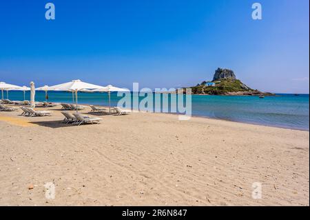 Liegestuhl und Sonnenschirm am wunderschönen Strand Agios Stefanos vor der Paradiesinsel Kastri - historische Ruinen und Paradieslandschaft an der Küste der Insel Stockfoto