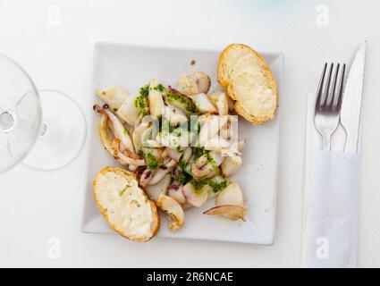 Gegrillte Calamari und zwei Stücke Brot, serviert auf einem Teller Stockfoto