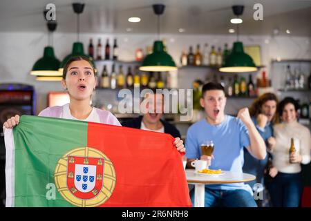 Fans mit der Flagge Portugals feiern den Sieg ihrer Lieblingsmannschaft in der Bierstube Stockfoto