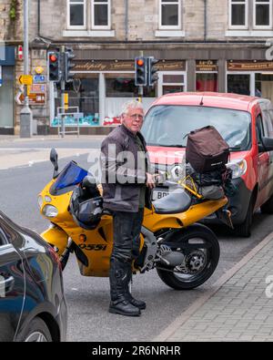 9. Juni 2023 Thurso, Schottland. Das ist ein Biker in Lederausrüstung, der neben seinem Triumph Daytona 955i auf der Straße angehalten hat, kurz davor, eine Zigarette zu drehen. Stockfoto