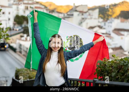 Aufgeregte junge Reisende, die auf der Straße mit der mexikanischen Flagge wedelt, Sportfan-Fan Stockfoto