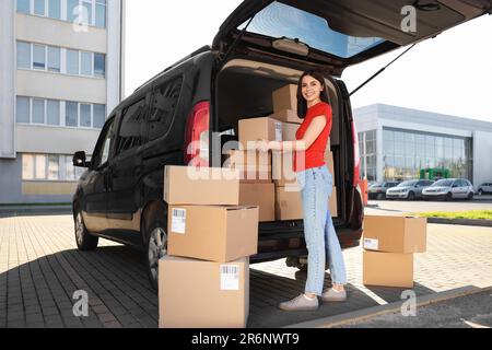 Ein Kurier nimmt das Paket aus dem Lieferwagen im Freien entgegen Stockfoto