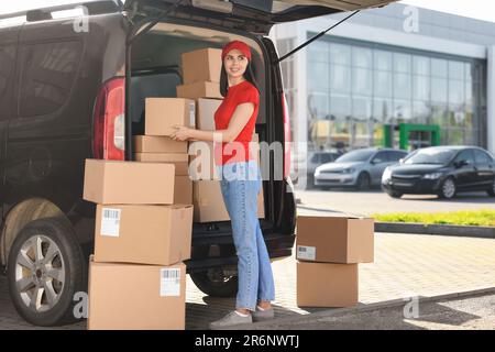 Ein Kurier nimmt das Paket aus dem Lieferwagen im Freien entgegen Stockfoto