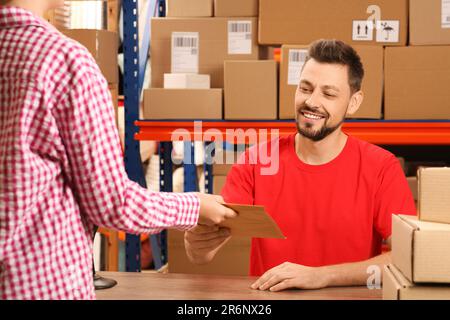 Frau, die ein Paket von einem Mitarbeiter der Post erhält Stockfoto