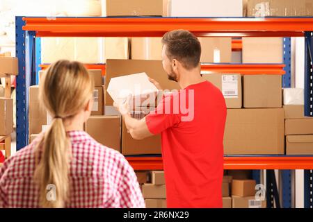 Frau und Arbeiter, die das Paket vom Postamt nehmen Stockfoto