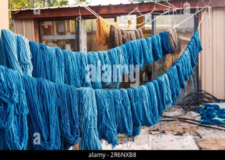 Im Trujillo Weaving Shop in Chimayo, New Mexico, USA, hängen farbenfrohe Sträucher aus handgefärbtem Garn an Seilen im Innenhof. Stockfoto