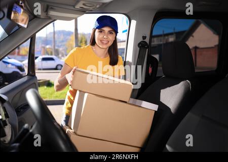 Der Kurier nimmt das Paket vom Auto ab. Lieferservice Stockfoto