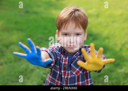 Kleiner Junge mit Händen in ukrainischen Flaggenfarben im Freien. Ich liebe das Ukraine-Konzept Stockfoto