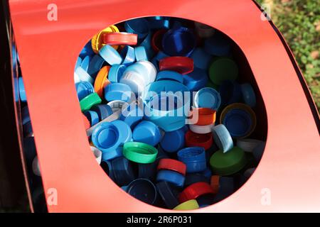 Verschieden farbenfrohe Flaschenverschlüsse in rotem Behälter. Kunststoffrecycling Stockfoto