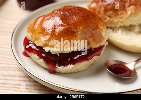 Frisch gebackene Soda-Wasser-Scones mit Preiselbeermarmelade auf Holztisch, Nahaufnahme Stockfoto