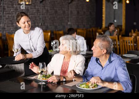 Weibliche Gastgeberin serviert Bestellung für ältere Ehepartner Stockfoto