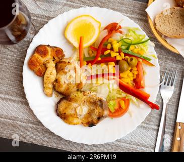 Gebackene Seehechtsteaks mit Gemüsesalat und Zitrone Stockfoto