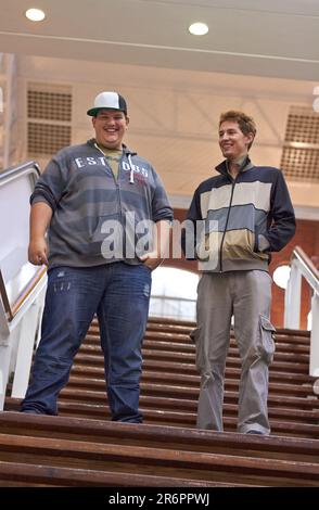 Schüler, Teenager, Freunde und Jungen, die mit einem Lächeln die Stufen zur Universität und Schule hinuntergehen. Gespräch, Gespräch und Diskussion über Männergruppengefühle Stockfoto