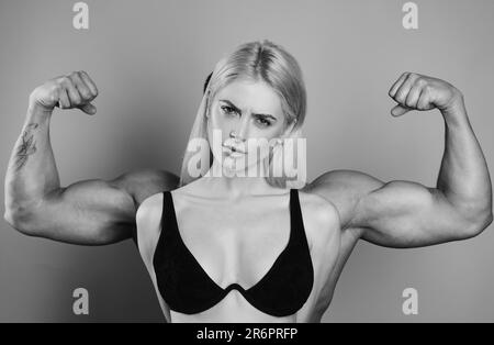 Lustiges Fitness-Paar. Funky Mädchen haben Bodybuilding Praxis, zeigen Bizeps. Eine junge weibliche Modell posiert mit männlichen großen Muskeln. Spaß an Fitness. Frauenmacht Stockfoto