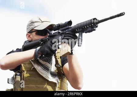 Soldat, Scharfschütze und draußen mit Zielen, Feld oder Natur für Krieg, Kampf oder Armee auf dem Land. Militärdienst, Schlachtfeld und Agent mit Waffe Stockfoto