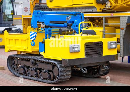 Gelbes Raupenfahrwerk mit blauem Teleskopkran zum Be- und Entladen. Stockfoto