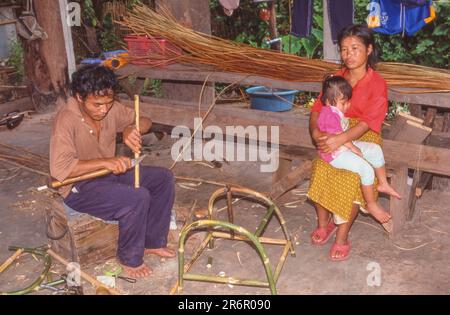 BANGKOK, THAILAND - 7. APRIL 2023: Während seine Frau und sein Kind zuschauen, stellt ein Handwerker Bambusmöbel in Nan her, einer Stadt im Norden Thailands, 688 km No Stockfoto