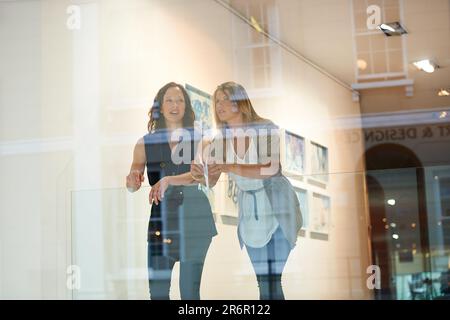 Frauen, Freunde zusammen und Ausstellung auf der Galerie, Konversation und kulturelle Wertschätzung. Frau, Kunstkritiker-Partnerschaft, die mit ins Museum schaut Stockfoto