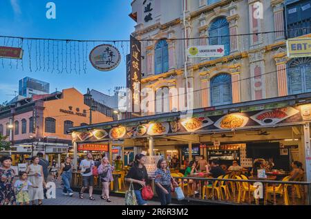 Touristen schlendern durch Chinatown, Singapur, oder essen in den halb offenen Restaurants der Gegend, die sich in renovierten traditionellen alten Häusern befinden Stockfoto