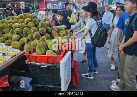 Chinesische Touristen an einem Straßenstand in Chinatown, Singapur, kaufen die beliebten, wenn auch stinkenden Durianfrüchte, Ein Genuss für viele in Südost- und Ostasien Stockfoto