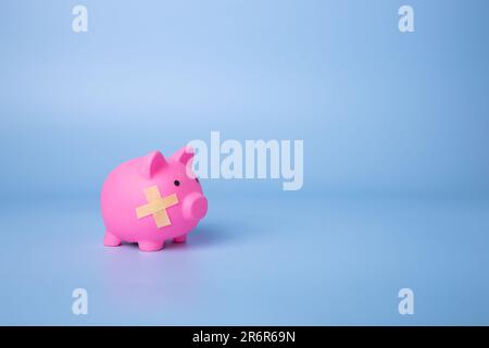 Schweinebank mit Pflasterverband auf blauem Hintergrund. Insolvenzkonzept Stockfoto