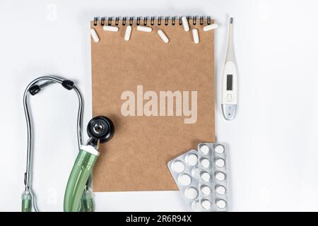 Medizinisches Modell - Notizblock mit Stethoskop, Pillen und Thermometer, Draufsicht, Platz für Text Stockfoto