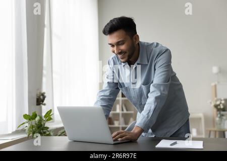 Glücklicher, erfolgreicher Projektleiter, der mit einem Notebook arbeitet Stockfoto