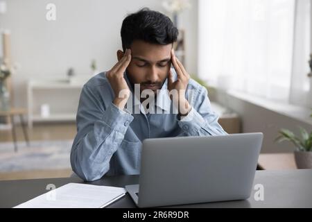 Ein kranker, junger indischer Angestellter, der sich müde und überarbeitet fühlt Stockfoto
