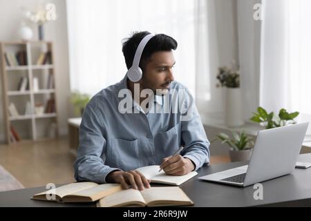 Engagierter indischer Student für kabellose Kopfhörer, der sich ein Online-Seminar ansieht Stockfoto